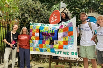 People holding up a home-made patchwork quilt banner at a march