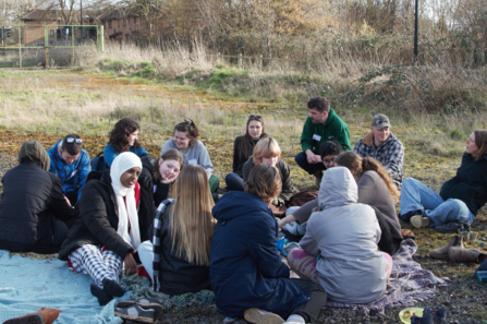 The Youth Leadership Group sit on the ground at Grow Wilder